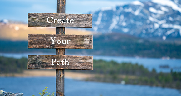 a sign stating create your path with a mountainous background with lakes