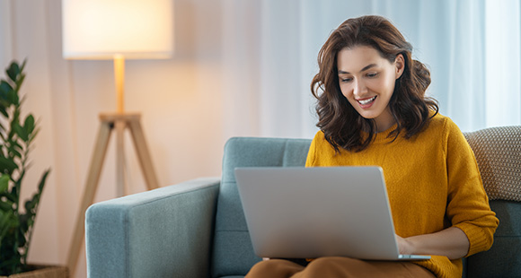 a lady smiling while using her laptop in her home